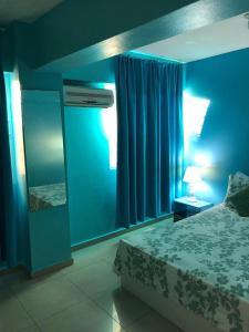 ein blaues Schlafzimmer mit einem Bett und einem Spiegel in der Unterkunft Apartamento Aquarel in Boca Chica