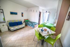 a living room with a table and green chairs at Dolly Monolocali in Porto Cesareo