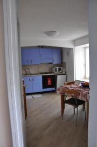 eine Küche mit blauen Schränken und einem Tisch in der Unterkunft Casa Tania in Pozza di Fassa