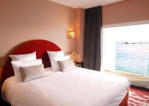 a hotel room with two beds and a large window at Hotel Mercure Roscoff Bord De Mer in Roscoff