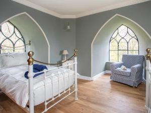 a bedroom with a bed and a chair and two windows at Brynkir Tower in Llanfihangel-y-pennant
