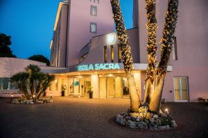 a building with palm trees in front of it at Hotel Isola Sacra Rome Airport in Fiumicino