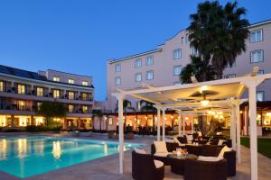 a hotel patio with a pool and tables and chairs at Hotel Isola Sacra Rome Airport in Fiumicino