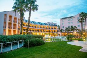 a large building with palm trees in front of it at Hotel Isola Sacra Rome Airport in Fiumicino