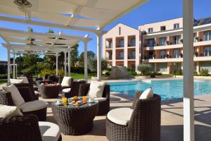 a patio with chairs and a table and a pool at Hotel Isola Sacra Rome Airport in Fiumicino