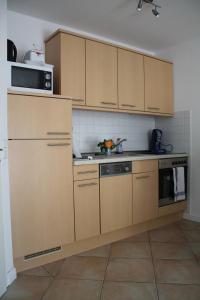 una cucina con armadi in legno, lavandino e forno a microonde di Ferienwohnung Charlotte a Ostseebad Karlshagen