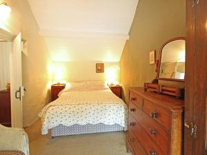 a bedroom with a bed and a dresser and a mirror at Buck Cottage in Pentraeth