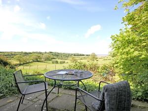 a table and chairs on a patio with a view at Buck Cottage in Pentraeth +10 photos