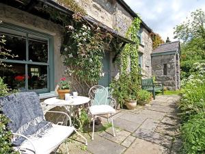 a patio with a table and chairs in front of a building at Buck Cottage in Pentraeth