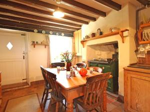 a kitchen with a wooden table and a green stove at Buck Cottage in Pentraeth