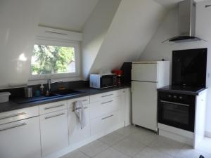 a kitchen with white cabinets and a sink and a microwave at Au coeur des vignes in Barr