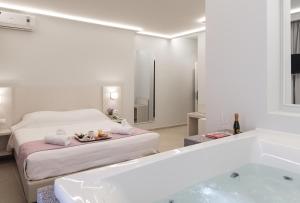 a white bathroom with a tub and a bed and a bath tub at Poseidonio Hotel in Tinos Town
