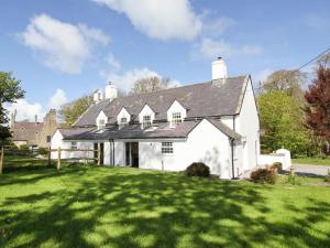 a large white house with a grass yard at Garden Cottage - Rhoscolyn in Rhoscolyn