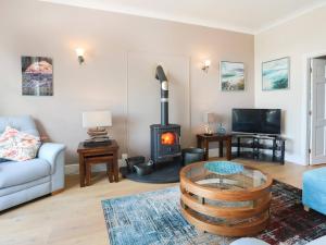 a living room with a wood stove and a couch at Gwylan Uchaf in Y Felinheli