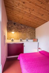 1 dormitorio con cama rosa y techo de madera en Mas Blau, en Sant Feliu de Boada