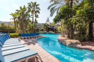 une piscine avec des chaises bleues et des palmiers dans l'établissement Melia Benidorm, à Benidorm