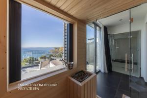 a room with a large window and a bathroom with a view at MaisonMe Boutique Hotel in Bardolino
