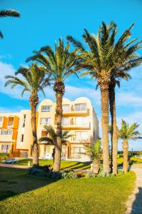 a group of palm trees in front of a building at AQI Skanes Resort in Monastir