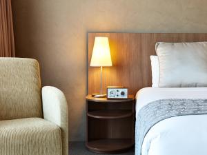 a hotel room with a bed and a chair and a lamp at Hotel Urban St Leonards in Sydney
