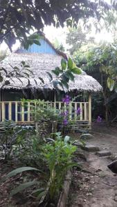 ein Haus mit Strohdach und ein paar lila Blumen in der Unterkunft Omshanty Jungle Lodge in Leticia