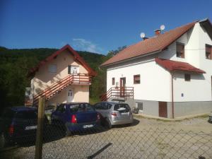 dos autos estacionados en un estacionamiento frente a una casa en Guesthouse Bubalo, en Drežnik Grad