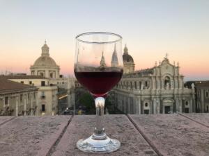 a glass of wine sitting on a table in front of a building at Dream House Duomo Catania in Catania