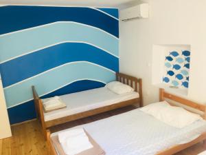 two beds in a room with a blue and white wall at Apartment Chillout House Novalja in Novalja