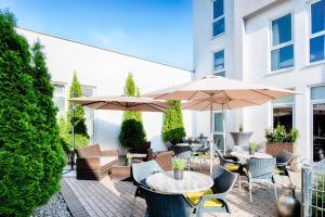 un patio avec des tables, des chaises et des parasols dans l'établissement ACHAT Hotel Hockenheim, à Hockenheim