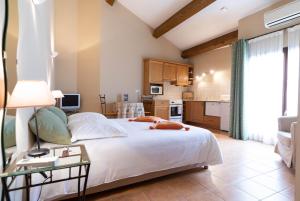 a bedroom with a large white bed and a kitchen at Le Relais Du Grand Logis in Mirabeau