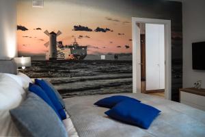 1 dormitorio con 1 cama y una pintura de un molino de viento en Apartament na Wyspie, en Świnoujście