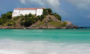 a white building on an island in the ocean at Pousada Gran Gaviota in Cabo Frio
