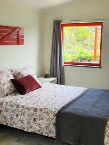 a bedroom with a bed with a large window at Casinha de Nesquim in Calheta de Nesquim