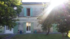 una gran casa de piedra con puertas verdes y árboles en La Petite Auberge, en Comps