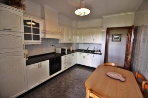 a kitchen with white cabinets and a wooden table at Casa Ardaña in Carballo