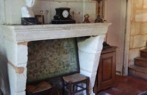 a fireplace with a clock on top of it at La Petite Auberge in Comps