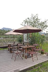 una terraza de madera con mesas, sillas y sombrilla en Nantou Sunmoon Lake Walami Homestay B&B, en Yuchi