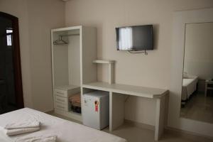 a bedroom with a desk and a tv on the wall at Hotel Alzira Imperial in São Lourenço