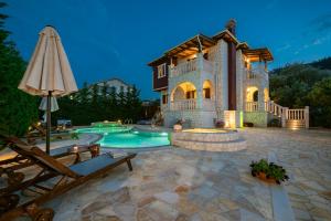 a large house with a swimming pool and an umbrella at Fairytale Villa in Lefkada Town