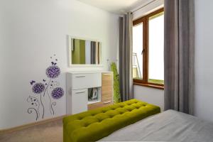 a bedroom with a green bench and a television at The Cozy Apartment in Varna City