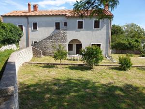 a large house with a brick wall and a yard at Apartments Stella Apsyrtides in Osor