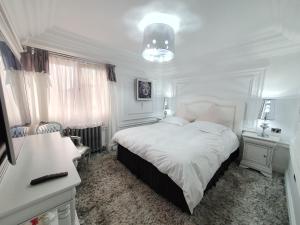 a white bedroom with a large bed and a chandelier at President in Ploieşti