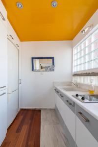 a kitchen with white cabinets and an orange ceiling at Red Beachfront Apartment in Kokkíni Khánion