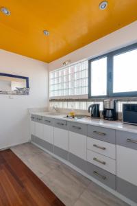 a kitchen with white cabinets and an orange ceiling at Red Beachfront Apartment in Kokkíni Khánion