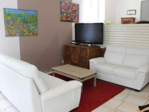 uma sala de estar com 2 cadeiras brancas e uma televisão de ecrã plano em le breuil em Sarlat-la-Canéda