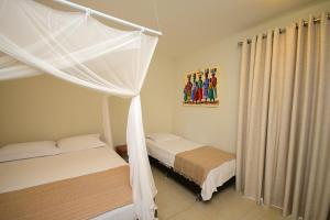 a bedroom with two beds and a canopy at Quintal da Arte Suites in Arraial d'Ajuda