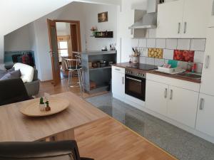 a kitchen and living room with white cabinets and a table at FeWo Nala in Trier