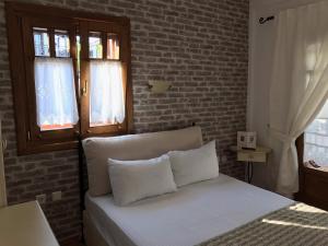 a bed with white pillows in a bedroom with a brick wall at Niriides in Ammouliani