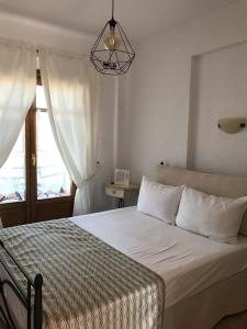 a bedroom with a bed with white sheets and a window at Niriides in Ammouliani