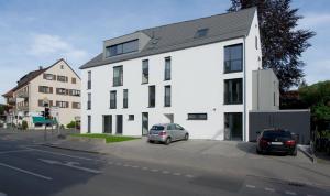 un edificio blanco con dos coches estacionados frente a él en Ferienwohnung Universität, en Tübingen