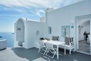 a white room with a table and chairs and the ocean at Canaves Elefas Villas in Imerovigli